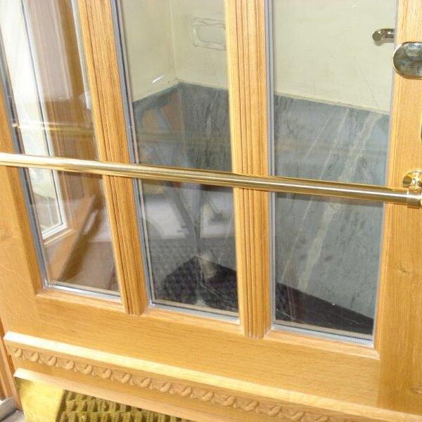 Nahaufnahme einer Haustür nach Maß mit polierten Messinggriffen und geschnitzten Holzdetails im Eichenfinish.