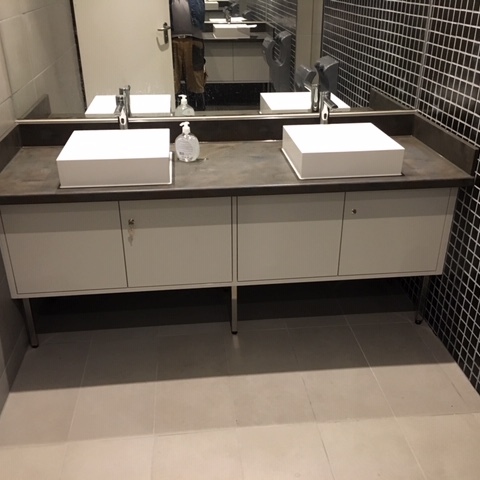 Maßgefertigte Badmöbel mit modernem Doppelwaschtisch, weißen Unterschränken und dunkler Arbeitsplatte in einem stilvollen Badezimmer mit Mosaikfliesen.