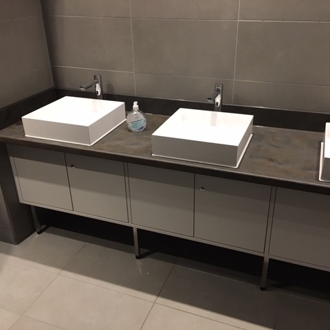 Modernes Badmöbel nach Maß mit zwei eckigen Aufsatzwaschbecken, dunkler Arbeitsplatte und weißen Unterschränken in einem stilvollen Badezimmer mit grauen Fliesen.