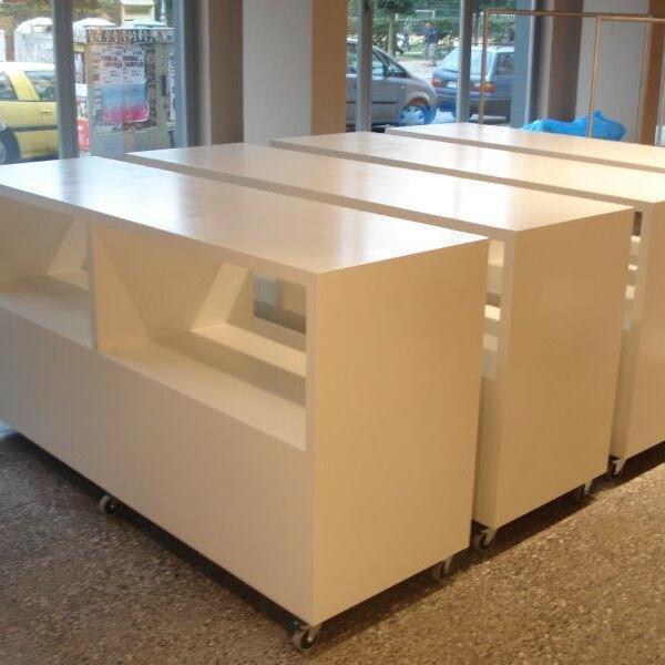 Maßgefertigtes, weißes Ladenregal mit Rollen in einem hellen Verkaufsraum, Außenansicht durch Fensterfront.