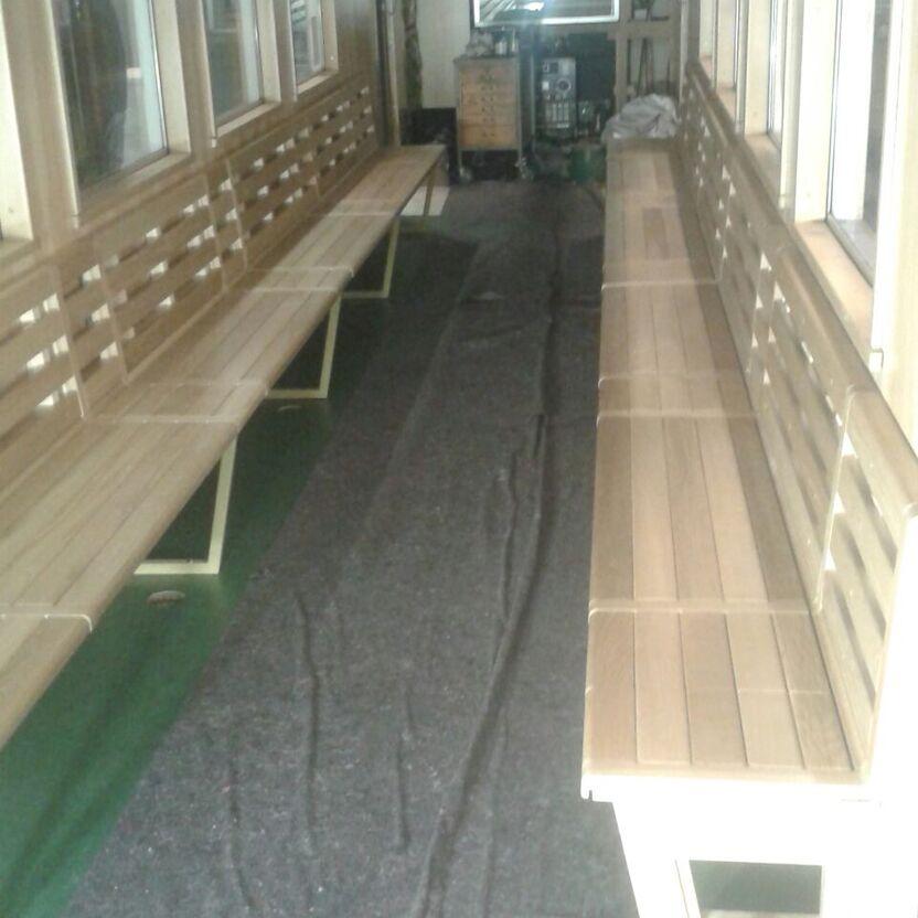 Innenraum eines Waggons mit maßgefertigten Holzbänken und grünem Teppichboden während des Ausbaus.