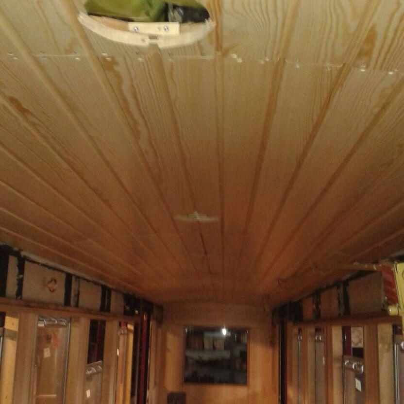Blick durch den Innenraum eines Waggons mit Holzvertäfelung während eines Umbaus nach Maß, mit sichtbaren Kabeln und Installationen.