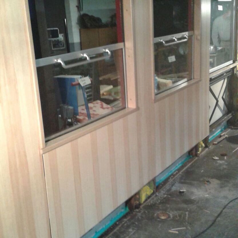 Teils renovierter Waggon mit Holzpaneelen und Fenstern, mit Baumaterialien am Boden, im Prozess des Wagonausbaus nach Maß.