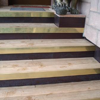 Treppe nach Maß mit abwechselnd dunklen und hellen Holzstufen, neben einer steinernen Statue.