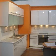 Moderne, weiße Küche nach Maß mit Edelstahlgeräten, umgeben von lebhaften orangefarbenen Wänden.