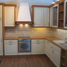 Gemütliche Küche nach Maß mit cremefarbenen Schrankfronten, Holzarbeitsplatte und Fliesenspiegel.