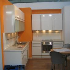 Stilvolle Küche nach Maß in Weiß mit modernen Geräten, umrahmt von leuchtend orangen Wänden.