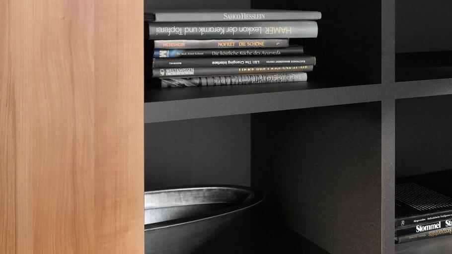 Detailaufnahme eines schwarz lackierten Regals mit Büchern und Schale in Kombination mit naturbelassenem Holz.