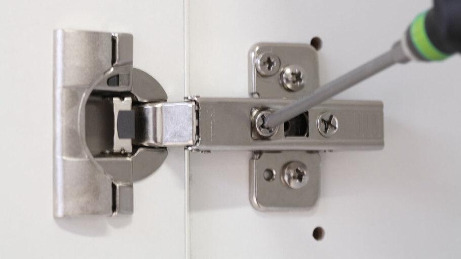 Detailaufnahme eines nachjustierbaren Türscharniers Detailaufnahme eines mit Schraubendreher nachjustierbaren Türscharniers