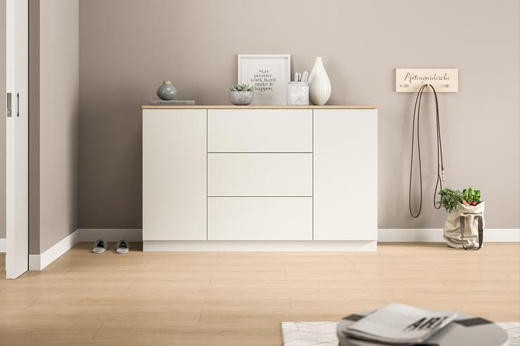 Eine maßgefertigte, weiße Kommode mit klaren Linien bietet diskreten Stauraum und eine minimalistische Ästhetik im Eingangsbereich des Hauses.